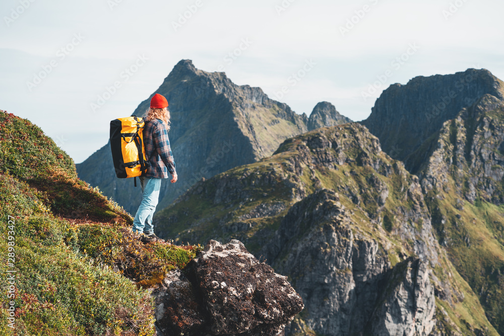 Brave tourist traveling on high mountains above sea. Hipster traveler with backpack standing on the edge cliff rock. Lifestyle adventure wanderlust