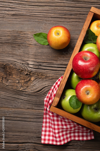 Ripe red and green apples in wooden box on a wooden table