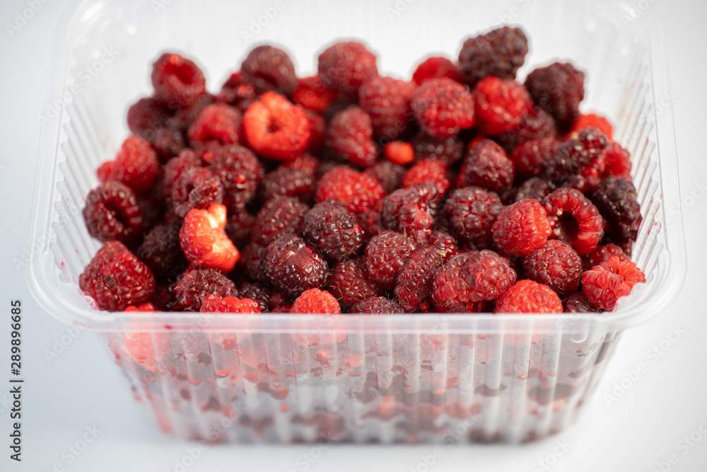 A lot of fresh raspberries in plastic packaging on a white background A lot of fresh raspberries in plastic packaging on a white background