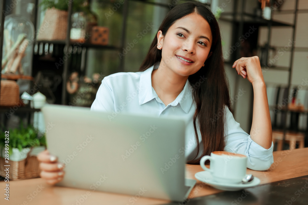 Asian woman in blue shirt working and drink coffee in coffee shop cafe vintage color tone Asian woman in blue shirt working and drink coffee in coffee shop cafe vintage color tone