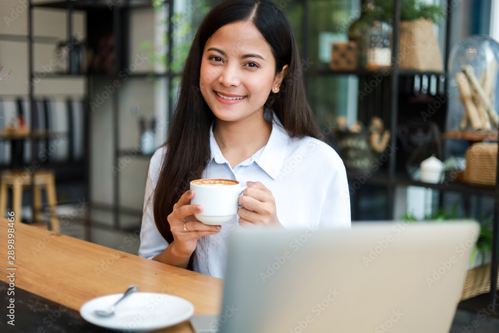 Asian woman in blue shirt working and drink coffee in coffee shop cafe vintage color tone Asian woman in blue shirt working and drink coffee in coffee shop cafe vintage color tone