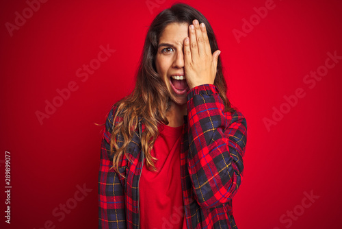 Young beautiful woman wearing casual jacket standing over red isolated background begging and praying with hands together with hope expression on face very emotional and worried. © Krakenimages.com