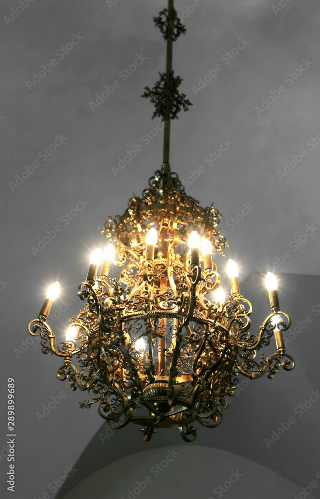 Old medieval chandelier with modern light bulbs in old castle. Concept of  meetting antiquity and modernity Stock Photo | Adobe Stock