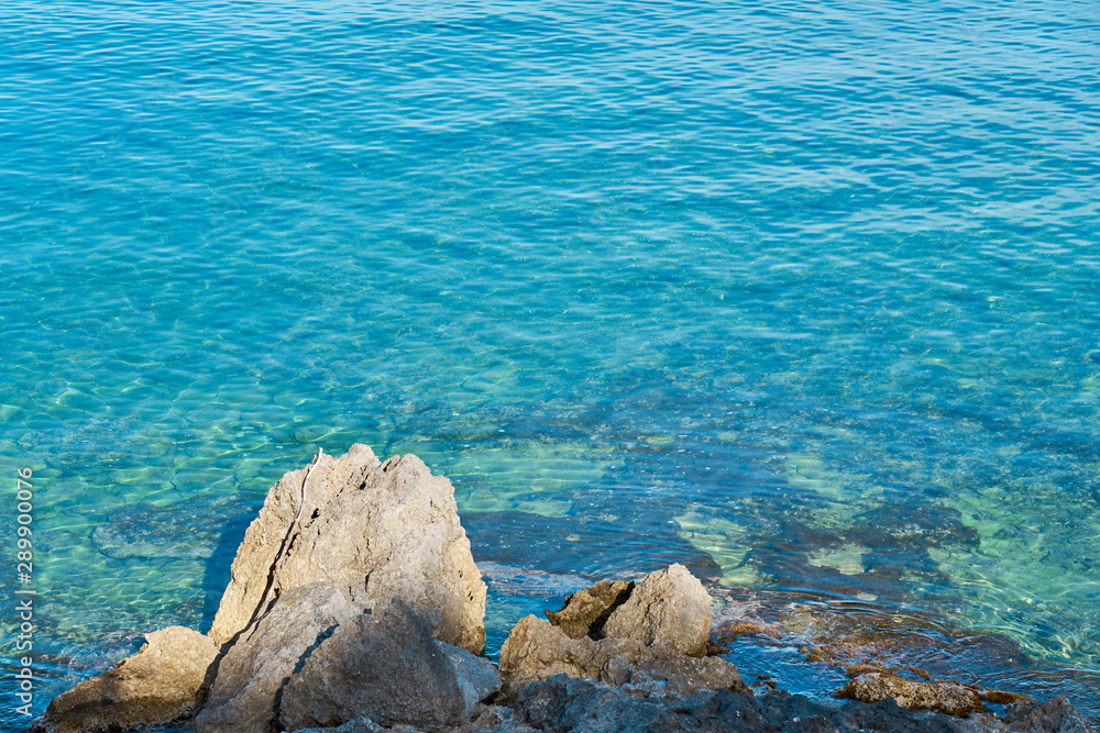 Stones on a sea coast of Colimbari, Crete, Greece against a blue sea water. Copy space. Stones on a sea coast of Colimbari, Crete, Greece against a blue sea water. Copy space.