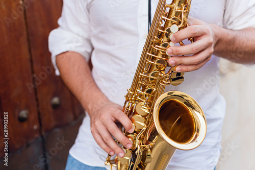 Close up of a man passionately playing the saxophone at the door of a building on the street