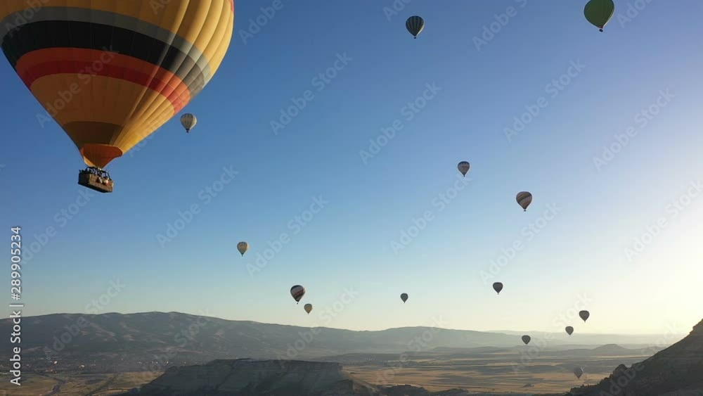Colorful hot air balloons are flying in the blue sky. drone follows hot air balloons. beautiful blue sky background. Hot air balloons in Cappadocia Colorful hot air balloons are flying in the blue sky. drone follows hot air balloons. beautiful blue sky background. Hot air balloons in Cappadocia
