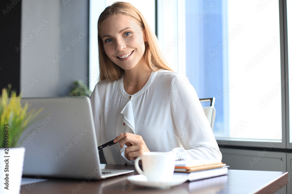 Beautiful business woman in smart casual wear working on laptop in the office Beautiful business woman in smart casual wear working on laptop in the office