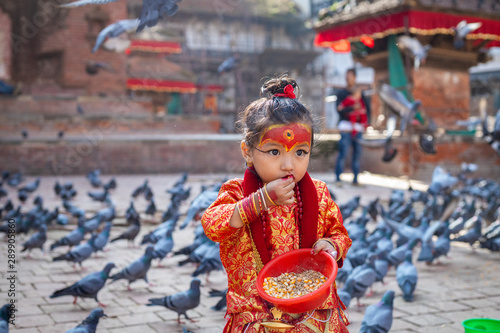 Little girl dressed as Kumari God feeding the pigeons at Kathmandu Durbar Square during Indra Jatra Festival photo