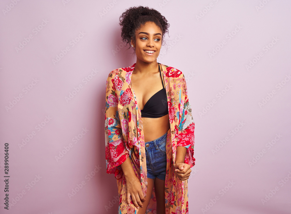 Young beautiful african american woman on vacation standing wearing bikini and colorful caftan Young beautiful african american woman on vacation standing wearing bikini and colorful caftan