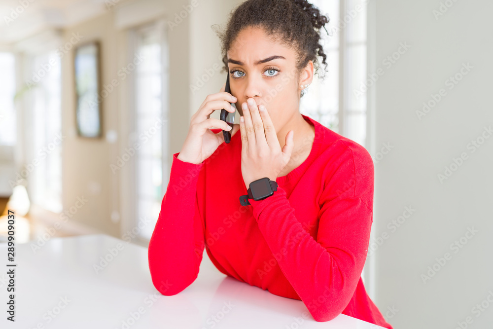 Young african american woman having a conversation talking on smartphone cover mouth with hand shocked with shame for mistake, expression of fear, scared in silence, secret concept Young african american woman having a conversation talking on smartphone cover mouth with hand shocked with shame for mistake, expression of fear, scared in silence, secret concept
