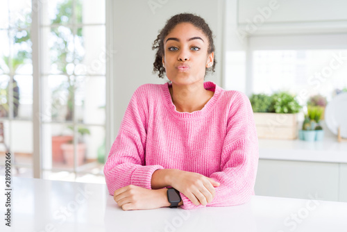 Free Download Beautiful african american woman with afro hair wearing casual pink sweater looking at the camera blowing a kiss on air being lovely and sexy. Love expression. - GFXLoad