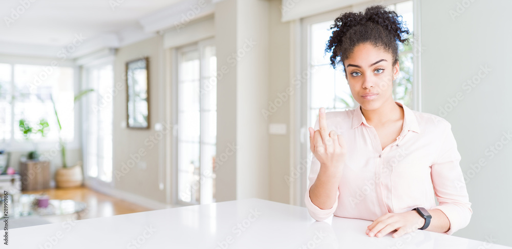 Wide angle of beautiful african american woman with afro hair Showing middle finger, impolite and rude fuck off expression Wide angle of beautiful african american woman with afro hair Showing middle finger, impolite and rude fuck off expression