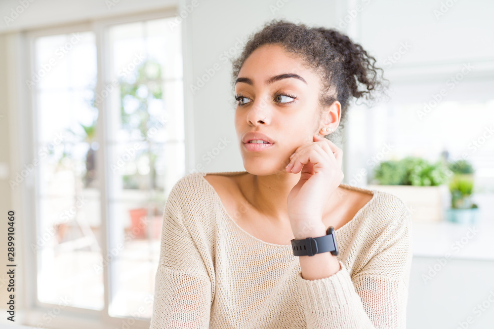 Beautiful young african american woman with blue eyes relaxing at home, with confident expression on face