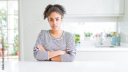 Beautiful african american woman with afro hair wearing casual striped sweater skeptic and nervous, disapproving expression on face with crossed arms. Negative person.