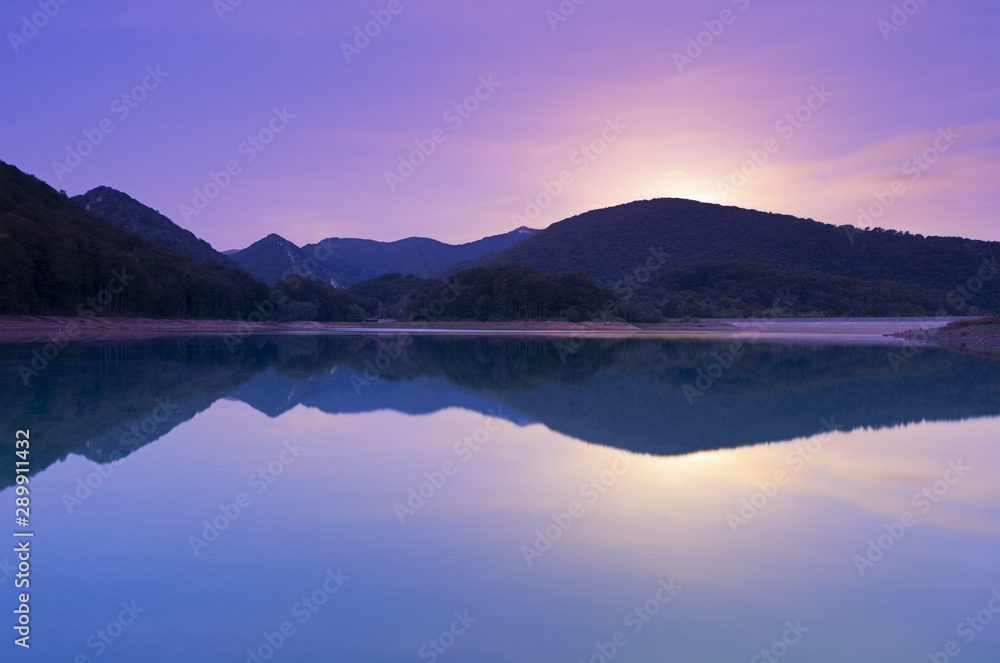 Full moon rise at dusk in the Lareo reservoir, Aralar mountain range, Euskadi