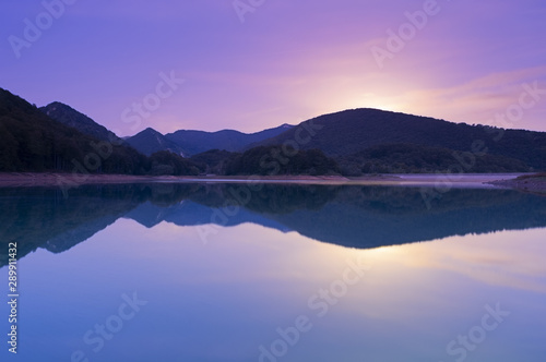 Full moon rise at dusk in the Lareo reservoir, Aralar mountain range, Euskadi