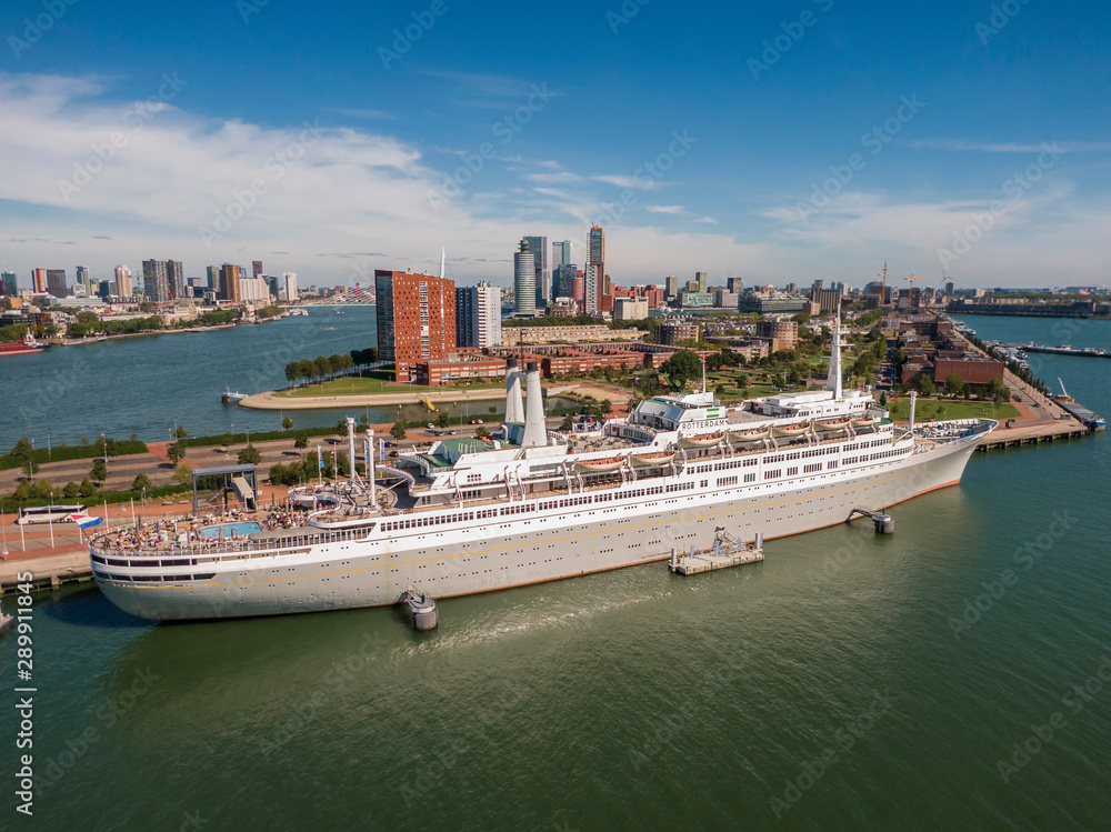 Fototapeta premium aerial of SS Rotterdam ship moared on Katendrecht land head with skyline of towers and Erasmus bridge in the background 