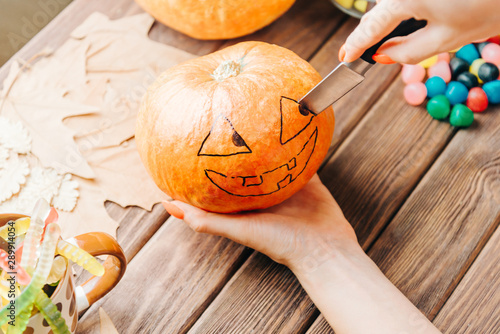 Photography View of female hands carve with knife a pumpkin for Halloween holiday