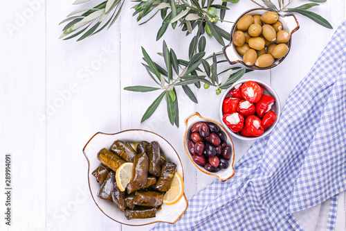 Traditional greek cuisine. Wrapped rice in grape leaves. Dolma with lemon, spices, various pickled olives and hot peppers. Fresh branches and homemade food.