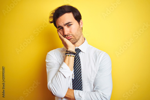 Young handsome businessman wearing elegant shirt and tie over isolated yellow background thinking looking tired and bored with depression problems with crossed arms.