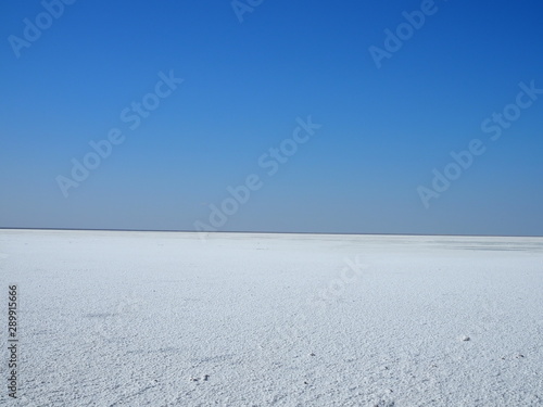 white surface of the lake covered with salt at sunrise