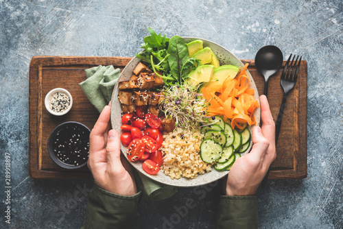 Vegetarian Buddha Bowl Salad In Male Hands On Wooden Serving Tray Background. Top View. Healthy Balanced Diet Food photo