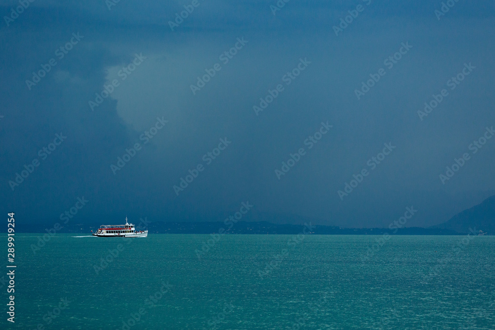 Lake Garda, Italy - August 13 2019. The view from the top to Lake Garda is fabulous. A gloomy sky awaiting a thunderstorm. Ship, boat, freshness, rain.