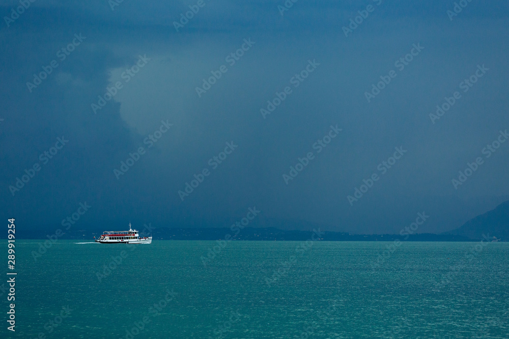 Lake Garda, Italy - August 13 2019. The view from the top to Lake Garda is fabulous. A gloomy sky awaiting a thunderstorm. Ship, boat, freshness, rain. Lake Garda, Italy - August 13 2019. The view from the top to Lake Garda is fabulous. A gloomy sky awaiting a thunderstorm. Ship, boat, freshness, rain.