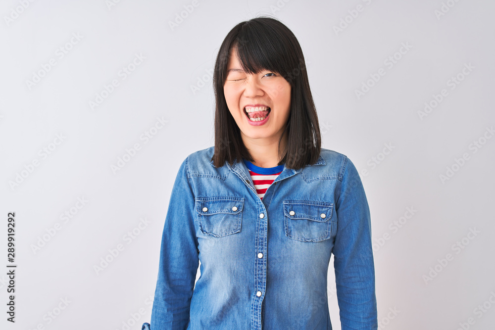 Young beautiful chinese woman wearing denim shirt over isolated white background winking looking at the camera with sexy expression, cheerful and happy face.