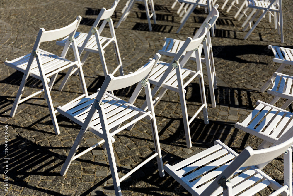 Symmetry of love: Rows of white folding chairs on lawn before a wedding ceremony in summer. White Folding Chairs at an Outdoor Wedding with flowers Symmetry of love: Rows of white folding chairs on lawn before a wedding ceremony in summer. White Folding Chairs at an Outdoor Wedding with flowers