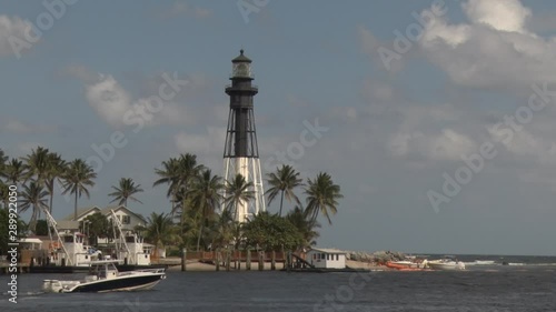 Pompano Beach Lighthouse at the Intracoastal Waterway at the Hillsboro Mile with a Boat Passing in a Spring Afternoon, Blue Sky with Scattered Clouds