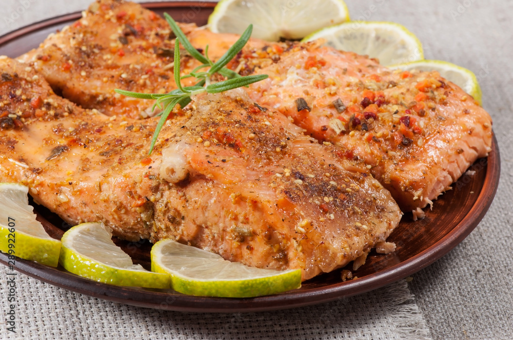 Grilled salmon with spices, lemon and rosemary, on a clay plate. Grilled salmon with spices, lemon and rosemary, on a clay plate.