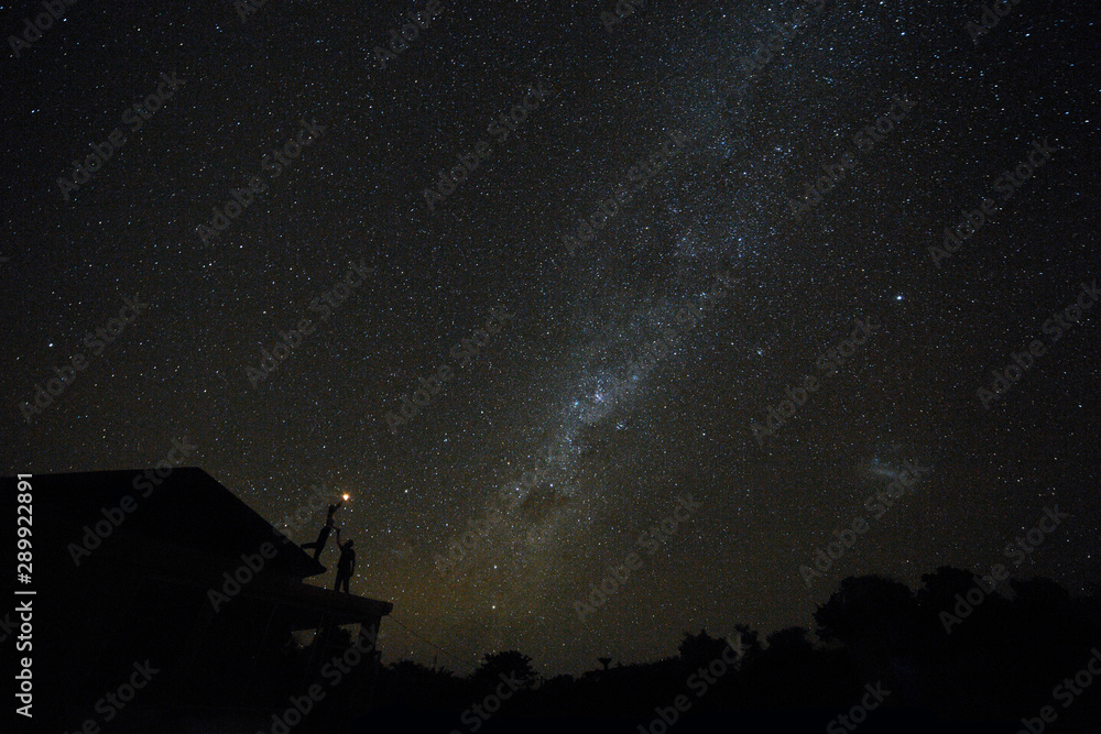 Couple on rooftop watching mliky way and stars in the night sky on Bali island Couple on rooftop watching mliky way and stars in the night sky on Bali island