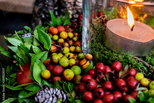 Hugge-style autumn decoration with a burning candle. Home decoration with red berries and small decorative apples.