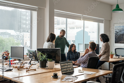 Smiling group of diverse designers meeting together in their office