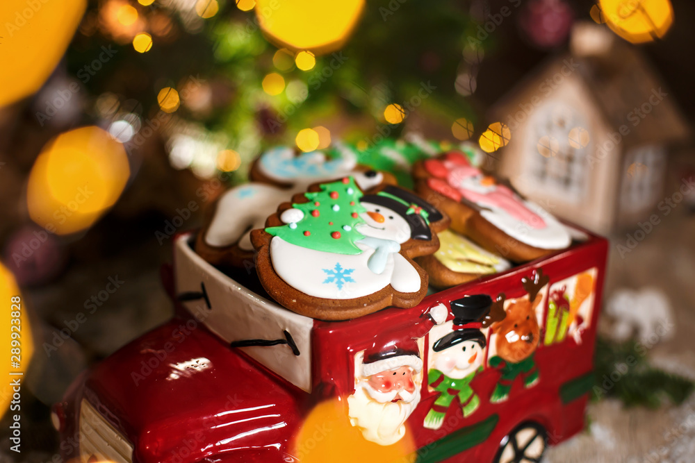 Holiday traditional food bakery. Decorative toy car with christmas Gingerbread cakes in cozy warm decoration with garland lights