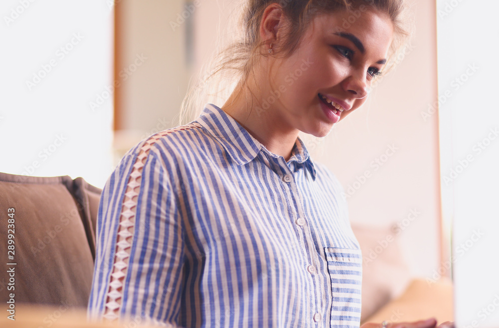 Fototapeta premium Happy brunette woman sitting on sofa with laptop