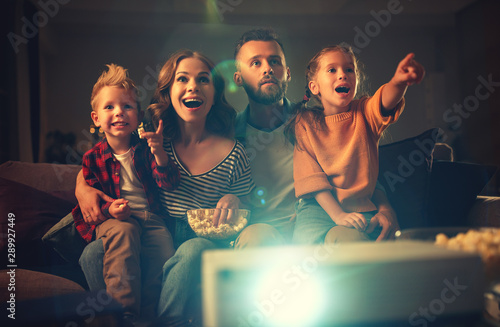 Bild auf Leinwand family mother father and children watching projector, TV, movies with popcorn in   evening   at home
