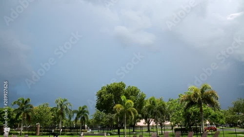 Lightning in Thick Gray Cloud Bank Over Neighborhood in a Bright Sunny Summer Afternoon in Boca Raton, Florida