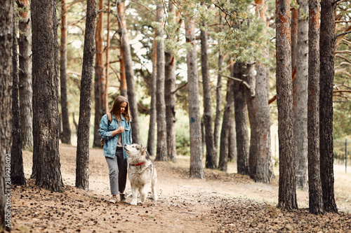 Woman Walking Dog. Young Girl with her Dog, Alaskan Malamute, Outdoor at Autumn. Domestic pet