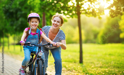 happy family mother teaches child daughter to ride a bike in the Park  . © JenkoAtaman