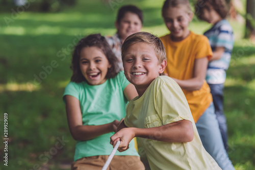 selective focus of happy kids competing in tug of war