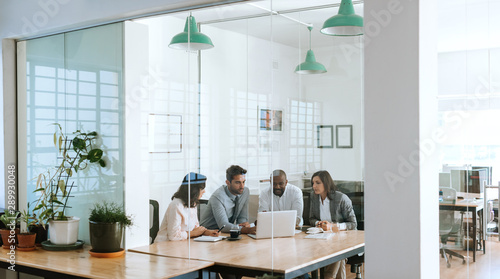Diverse businesspeople using a laptop together in an office boardroom