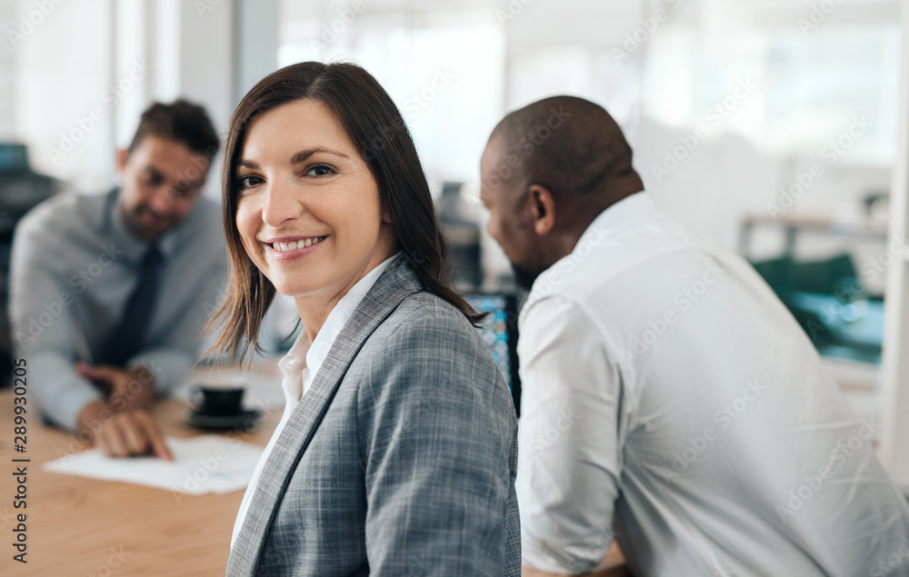 Fototapeta premium Smiling businesswoman sitting in an office meeting with colleagues