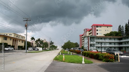 Big Rain Storm with Gray Clouds Approaching Condos on Street with Car Driving By in a Summer Morning in Pompano Beach, Florida