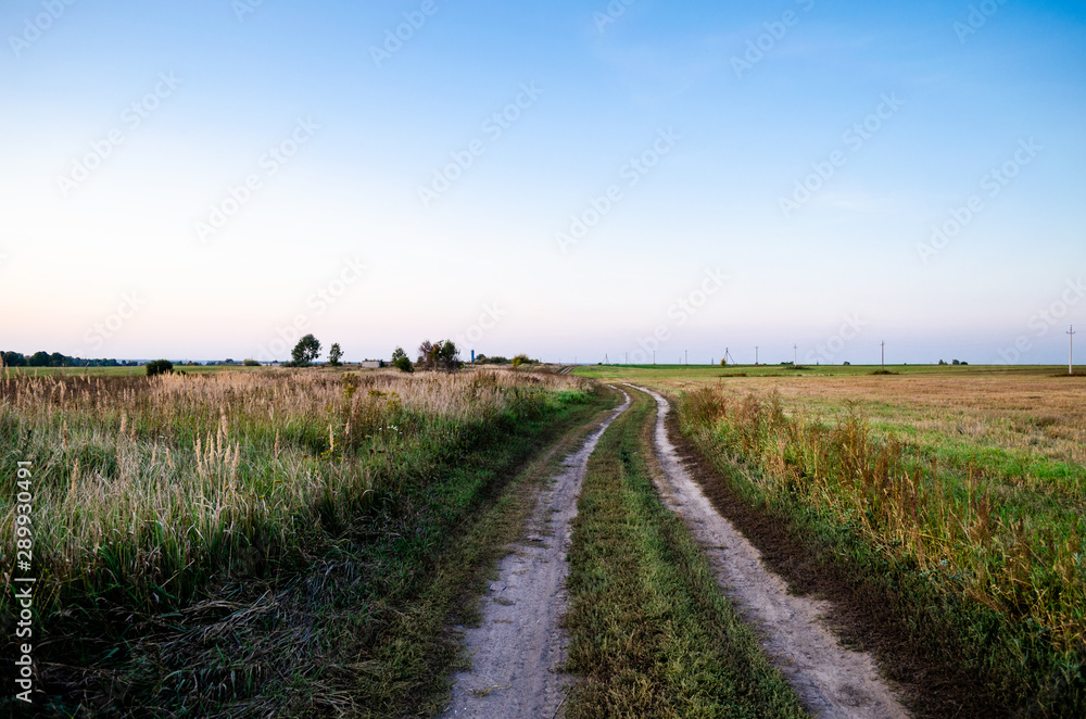 An empty rural road through empty fields. Clean autumn fields.