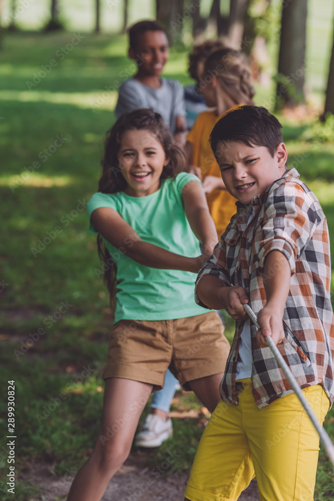 selective focus of positive multicultural kids competing in tug of war selective focus of positive multicultural kids competing in tug of war