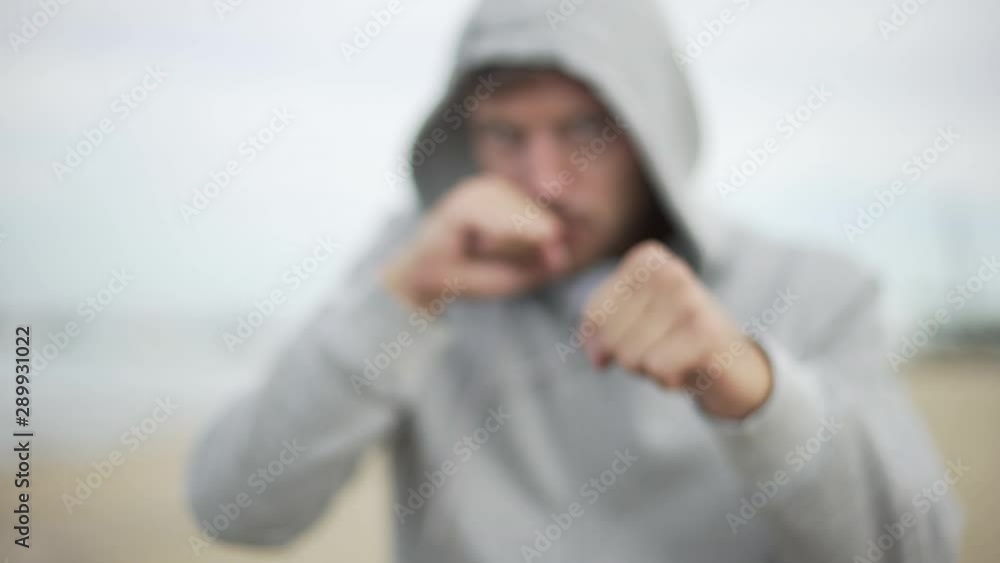 Portrait slow motion of handsome young man with a gray hoodie training and punching by the sea. Focus on hands. Portrait slow motion of handsome young man with a gray hoodie training and punching by the sea. Focus on hands.