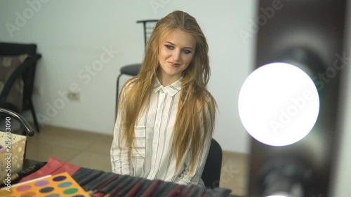 Makeup artist work in her beauty studio. Woman applying by professional make up master. Beautiful make up artist make a makeup for redhead model with freckles. She use a palette