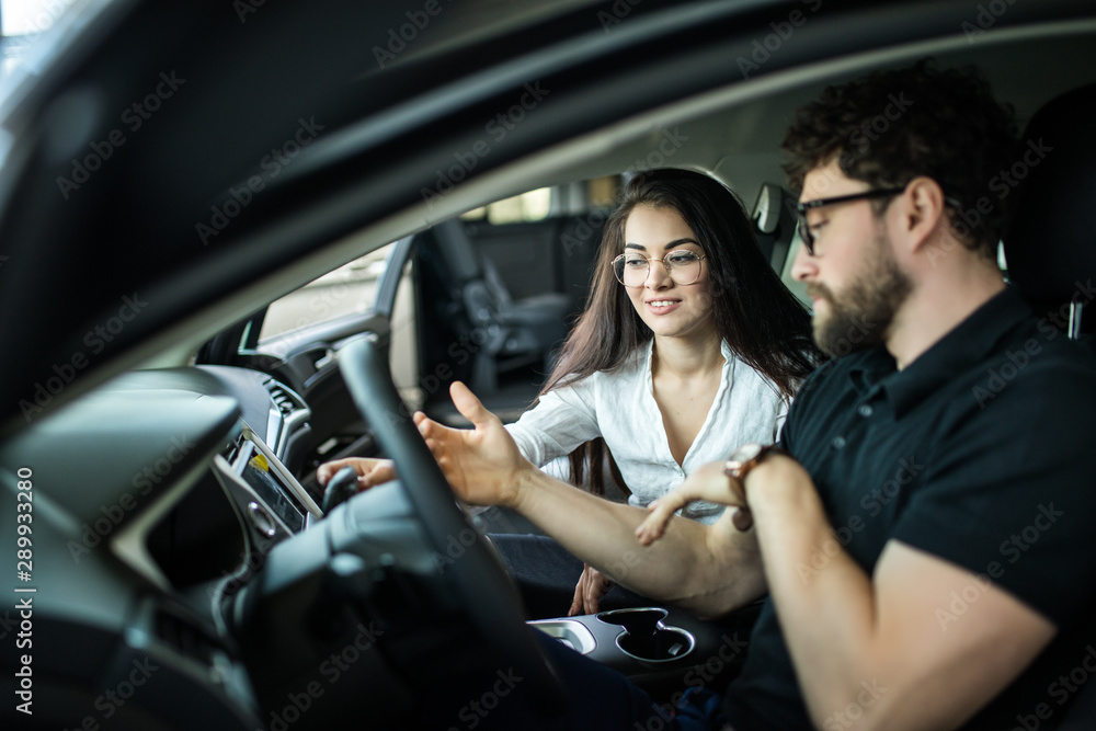 Sales manager woman describing car to customer in showroom Sales manager woman describing car to customer in showroom
